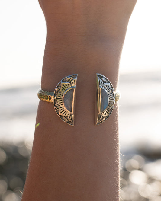 silver and gold bracelet with moon design at the beach. 