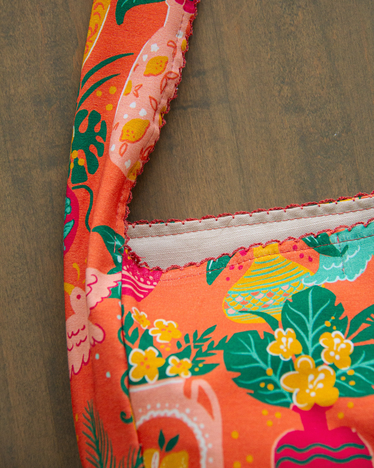 Close up of a colorful printed tropical tote bag with a lace trim in orange and teal. 