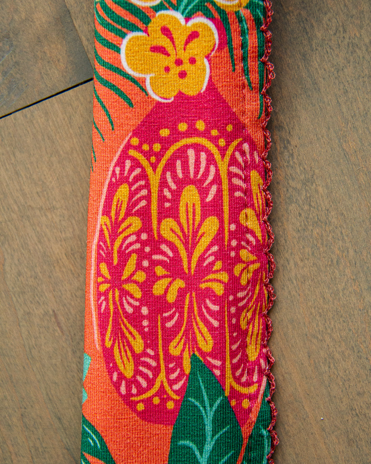 The strap of a hobo tote bag with a maximalist floral  tropical print on it. 