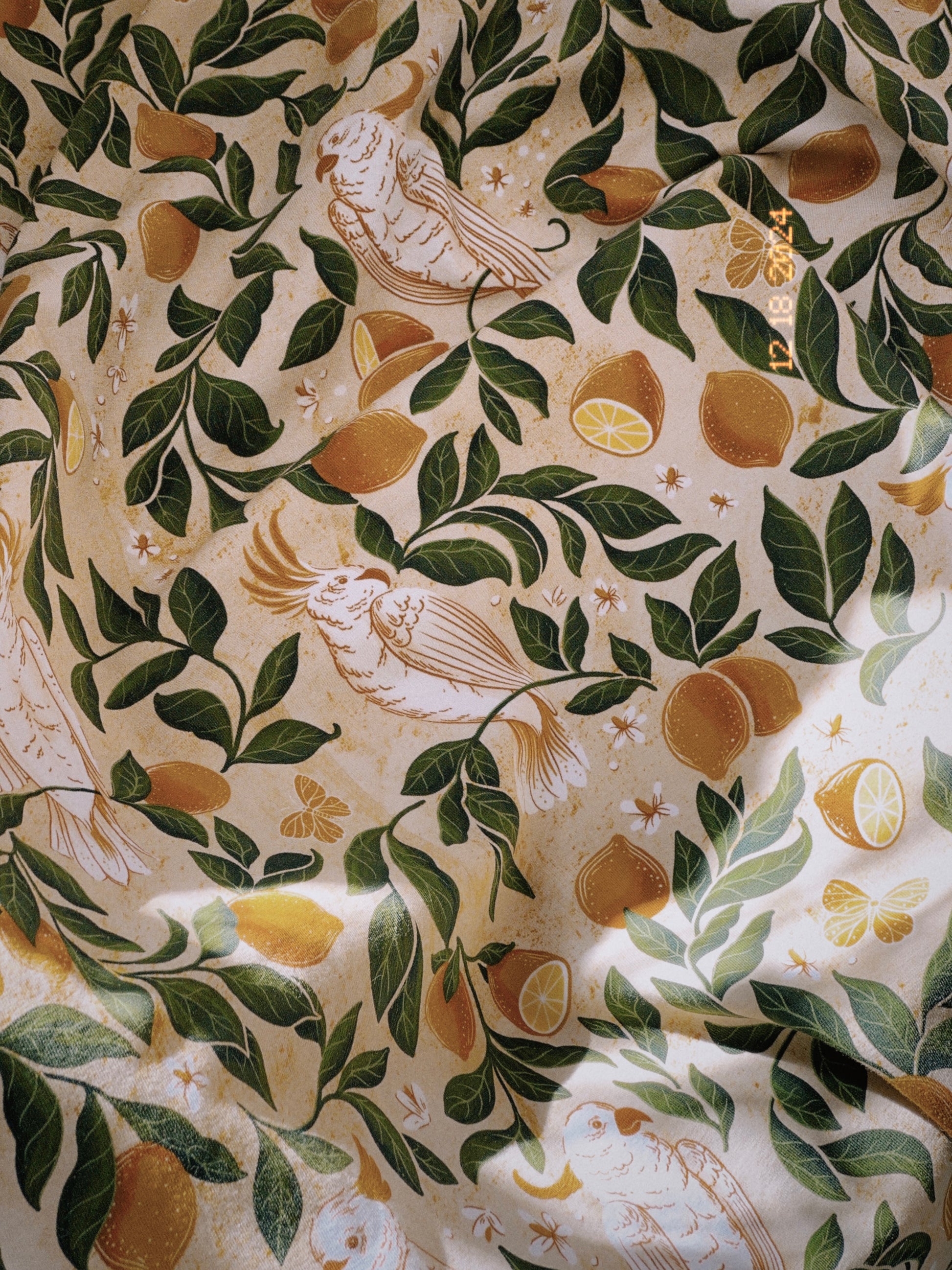 A heavy, sumptuous cotton jersey fabric printed with painterly leaves, lemons, and tropical birds. 
