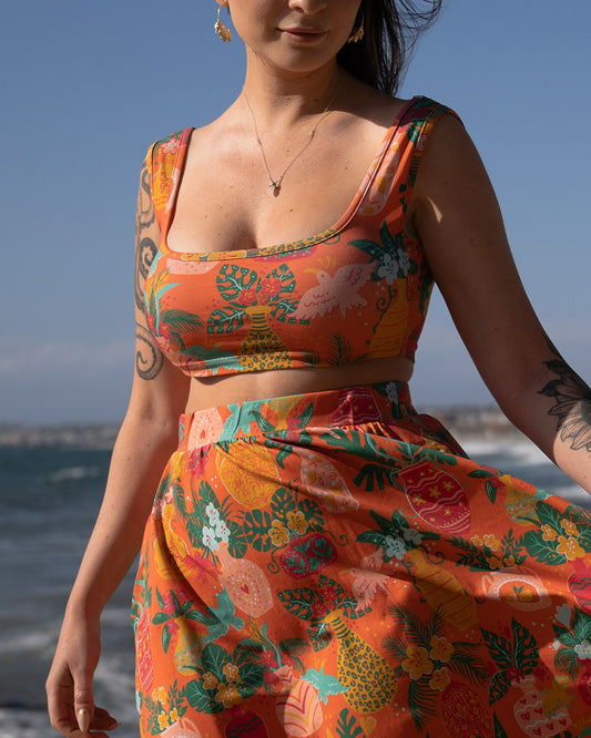 A woman at the beach wearing a colorful printed cropped tank top for summer fashion. 