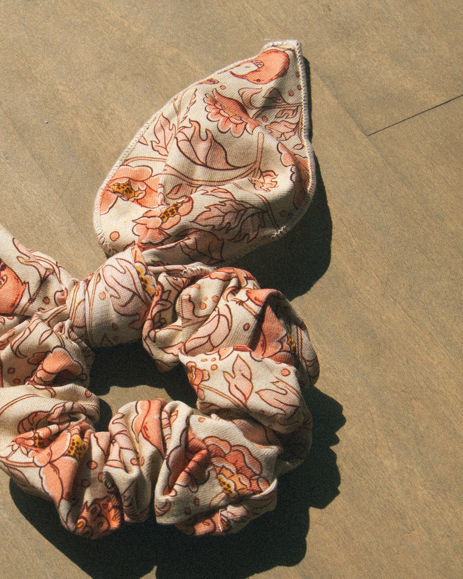 A pink floral printed scarf scrunchie hair tie. 
