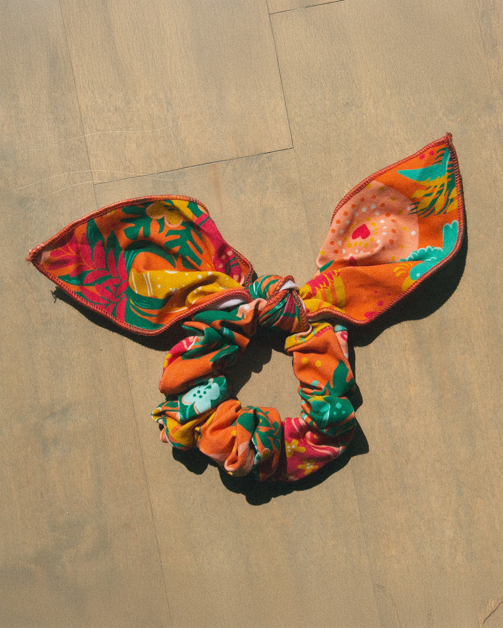 A colorful tropical print scrunchie hair tie with a bow. 